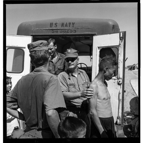      “How do you say, ‘where does it hurt?’” Doctor Hubbell asks PN3 Bruce Kohfield (back to camera) to translate.  Bruce was one of the few Seabees to have completed the Vietnamese language school back in Davisville. Bruce joins the MEDCAP field trips each week to help the doctors and corpsmen communicate with the villagers.